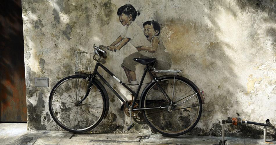 street art - vélo posé contre un mur avec deux enfants dessinés 